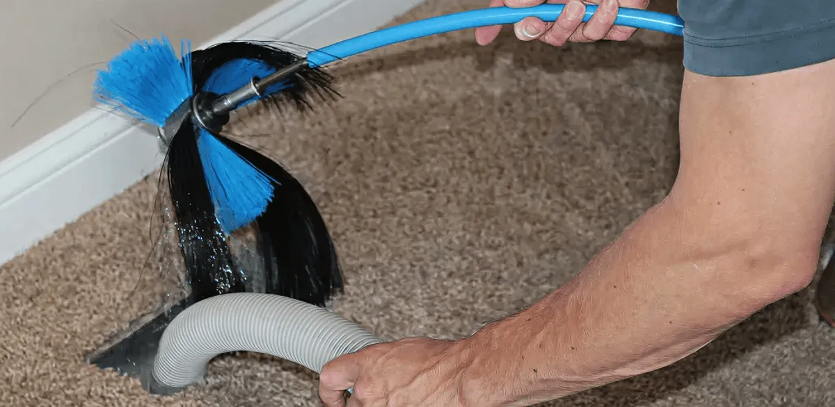 Dryer vent cleaning technician brushing lint from a vent line in Tempe, AZ