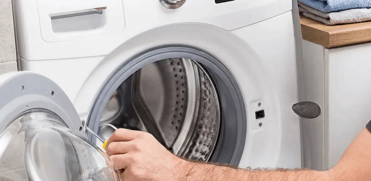 Handyman repairing a front-load washing machine and inspecting the drum in Tempe, AZ